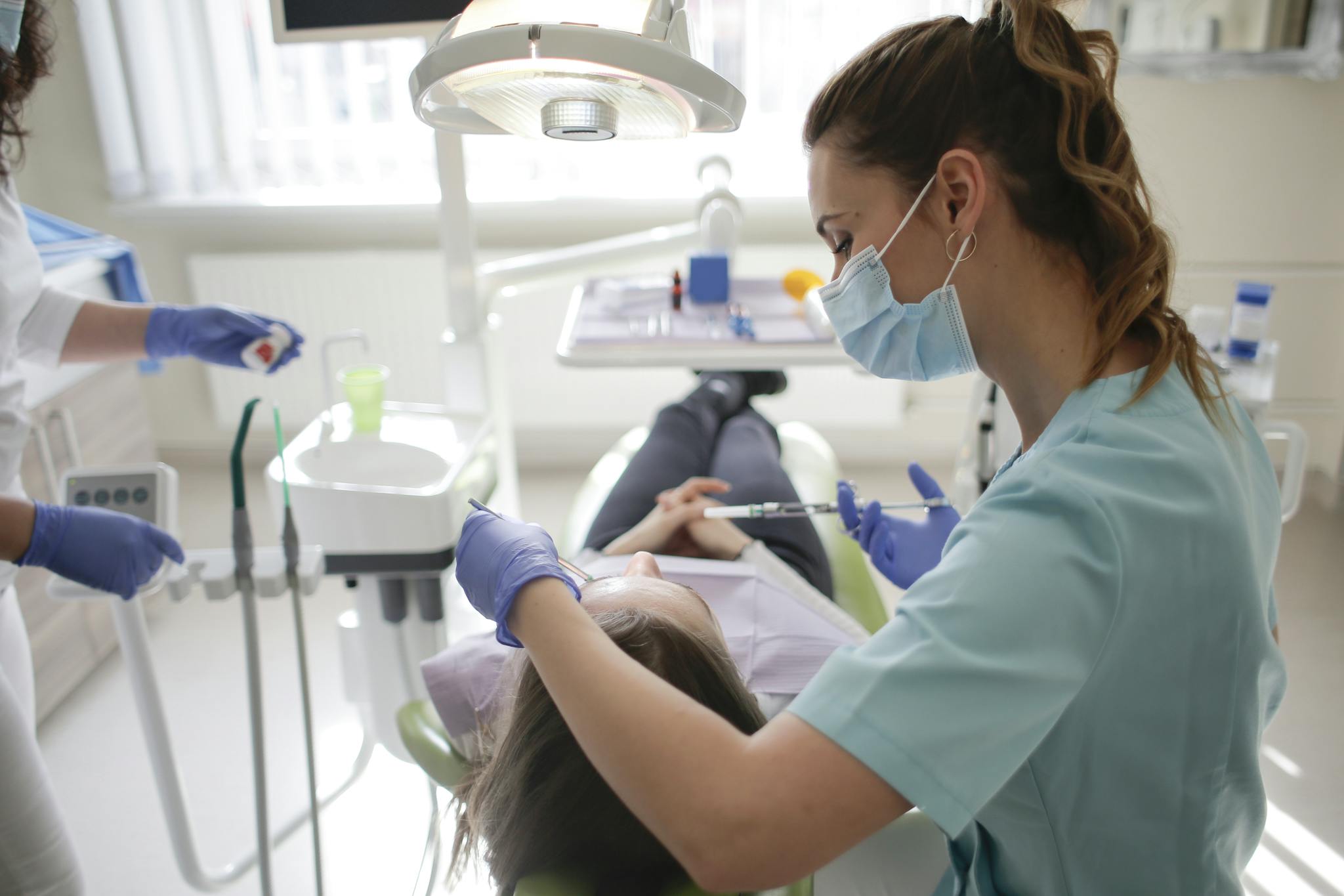 A female dentist performs dental treatment on a patient in a modern clinic.